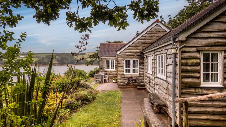 The exterior of Powders and its garden, with the Helford River in the background, Cornwall